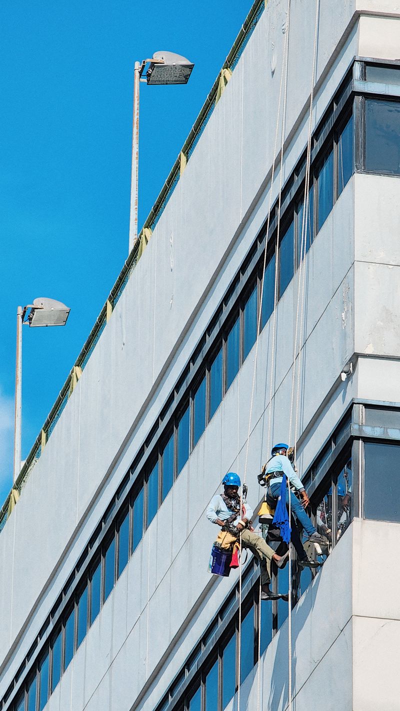 Trabajador con acceso por cuerda en una fachada azul
